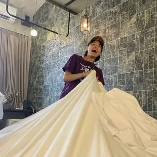 웃으며 침대 시트를 갈고 있는 청소 스태프